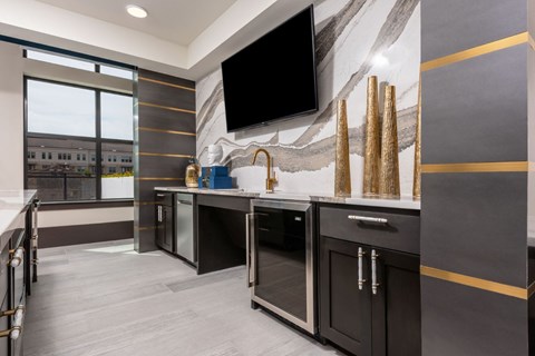 A modern kitchen with dark cabinets and a flat screen TV mounted on the wall.