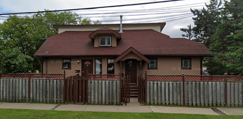 A house with a brown roof and a fence in front.