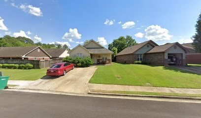 A red car is parked in front of a house.