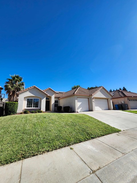 A house with a white garage door is in front of a palm tree.