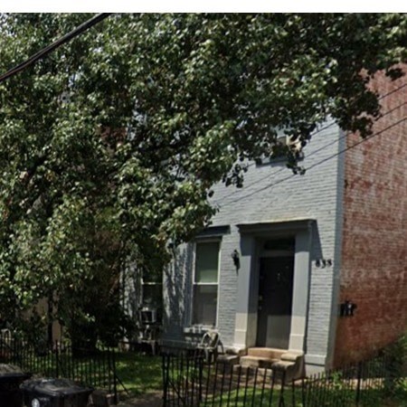 A house with a black gate and a tree in front.