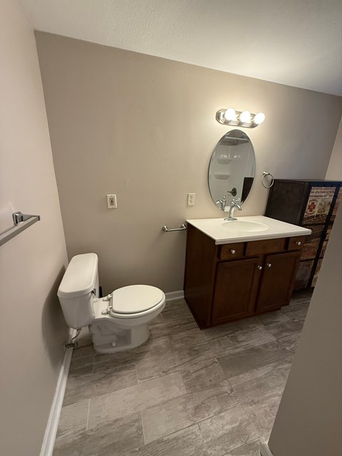 A bathroom with a toilet, sink, and mirror.
