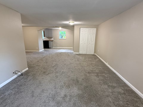 A spacious room with a carpeted floor and a white door.