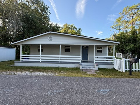 A small house with a porch and a white picket fence.