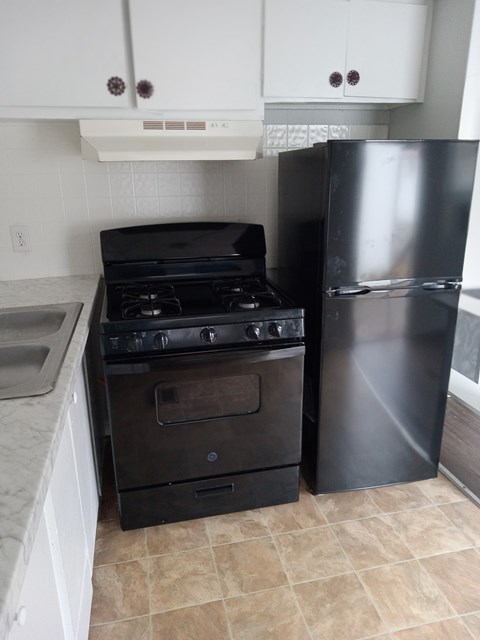 A black stove and refrigerator in a kitchen.