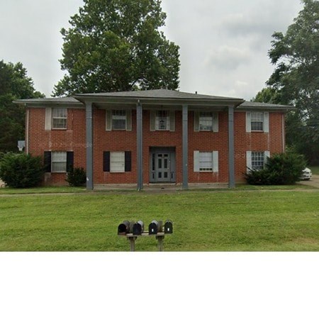 A red brick building with a grey roof and a mailbox in front.
