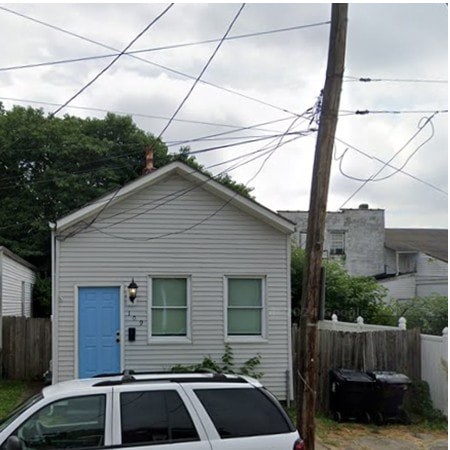 A small house with a blue door and a car parked in front.