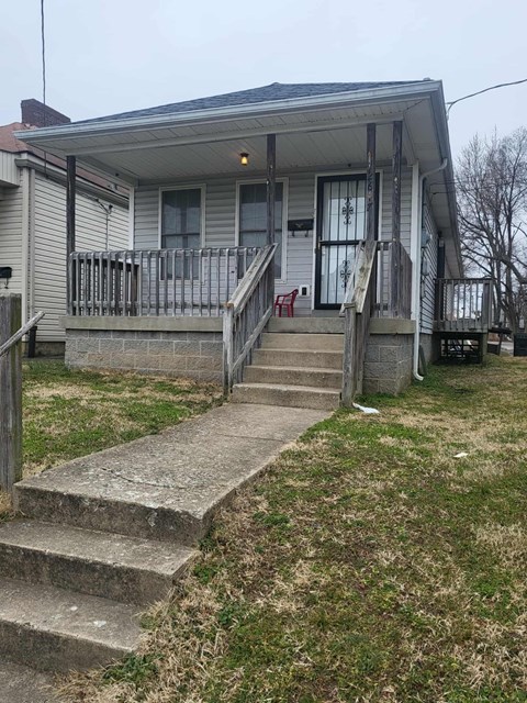 A house with a grey siding and a porch with a red chair.