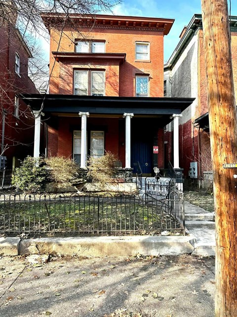 A red brick house with a black iron fence in front.