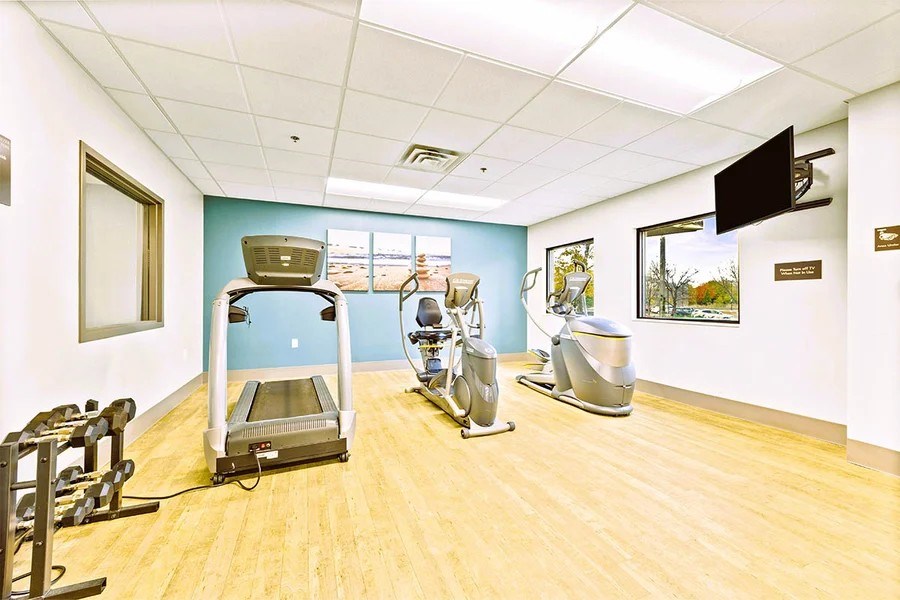 A gym room with a treadmill, weights and exercise bike.