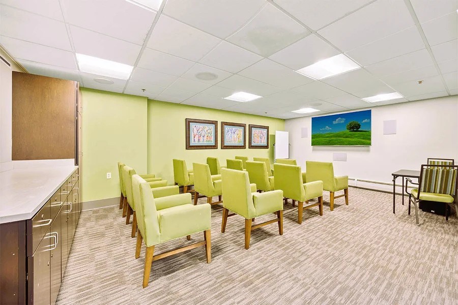 A conference room with green chairs and a painting on the wall.