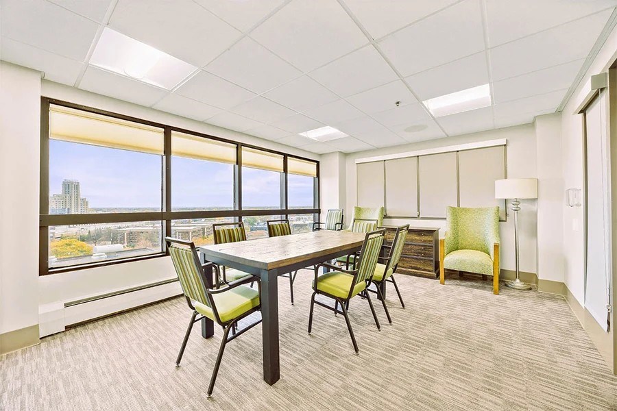 A conference room with a table and chairs and a view of the city outside the window.