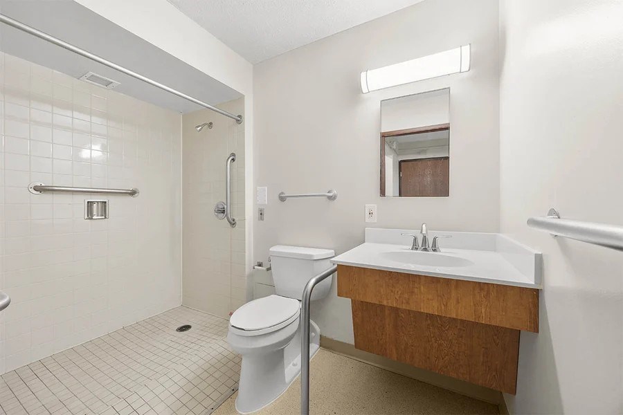 A white bathroom with a toilet, sink, and shower.