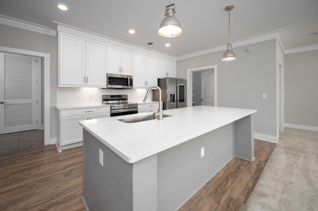 A kitchen with white cabinets and a white island.