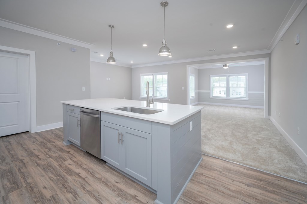 A kitchen with a white countertop and wooden flooring.