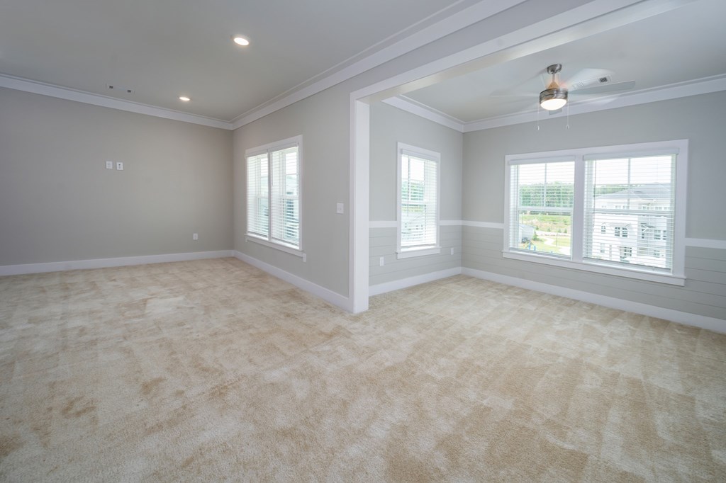 A spacious room with a carpeted floor and a ceiling fan.