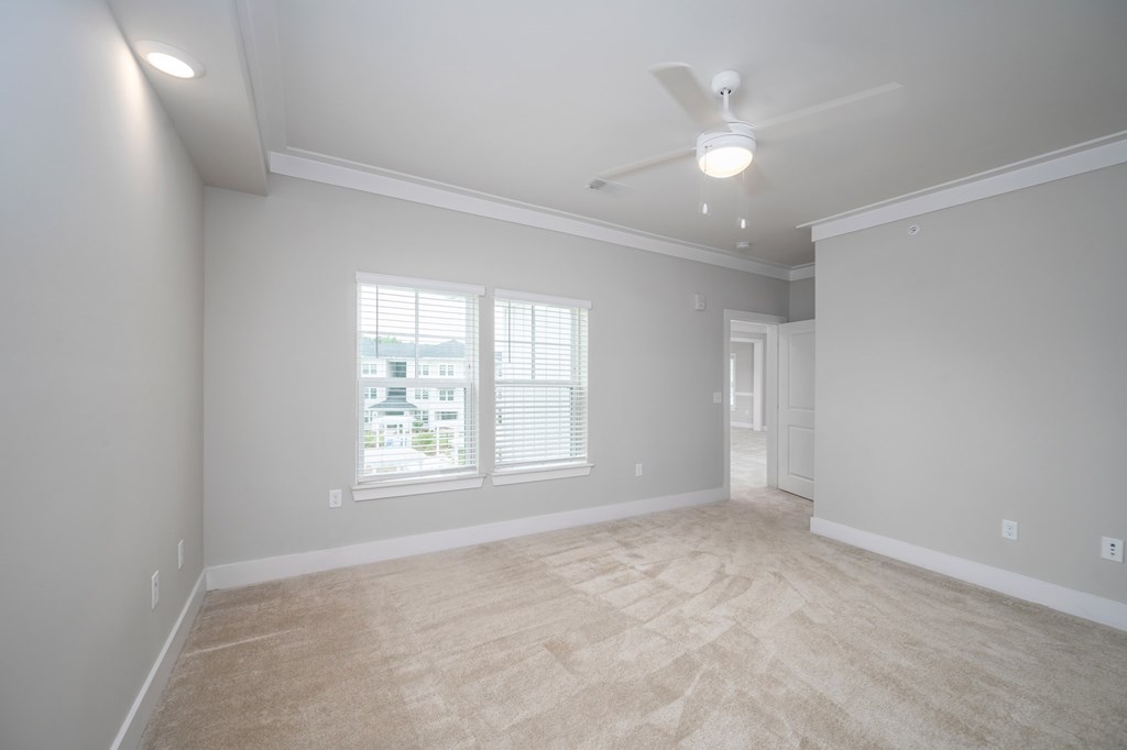 A spacious room with a ceiling fan and a window with blinds.