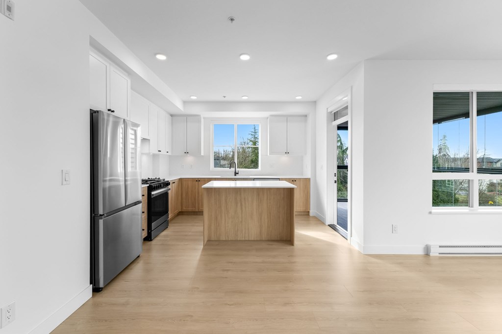 A modern kitchen with wooden floors and stainless steel appliances.