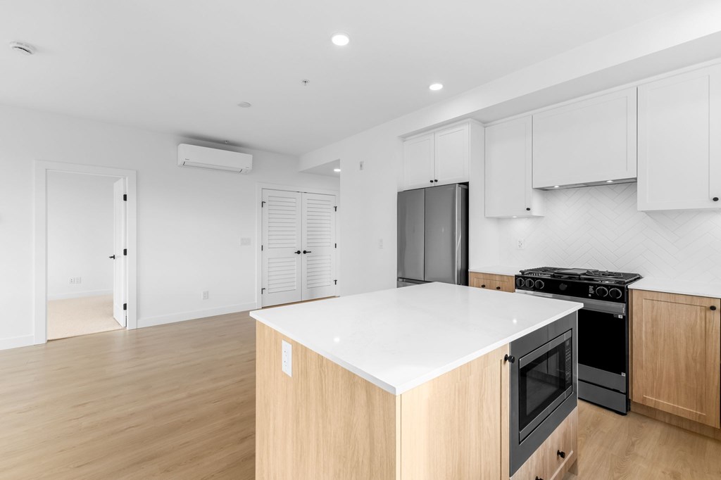 A kitchen with a white countertop and wooden cabinets.