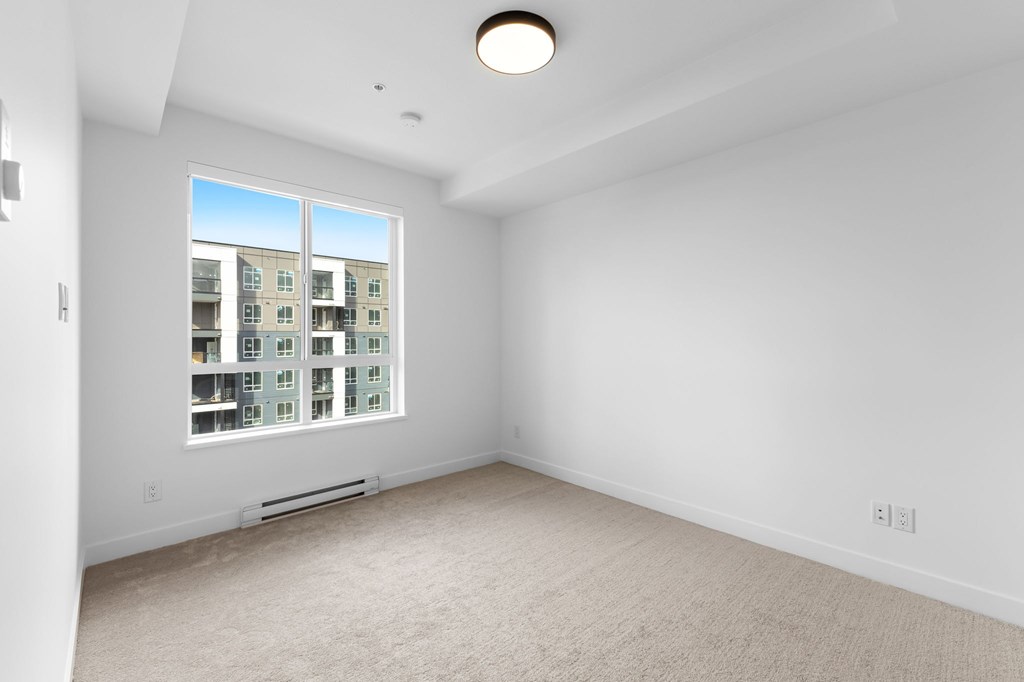 A spacious, empty room with a large window overlooking a building.