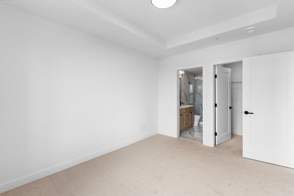 A white room with a carpeted floor and a doorway leading to another room.