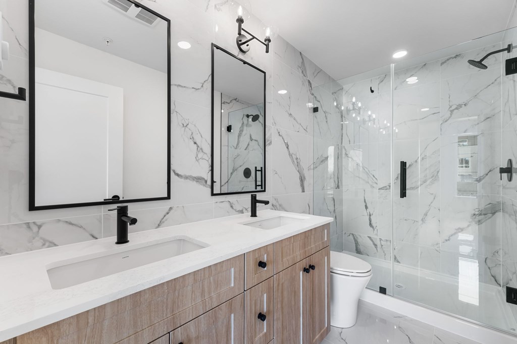 A bathroom with a marble wall and a wooden vanity.