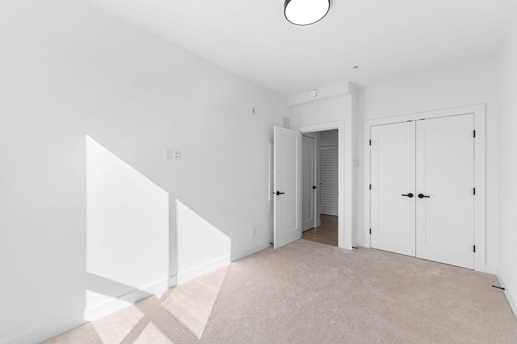 A white room with a carpeted floor and a skylight.