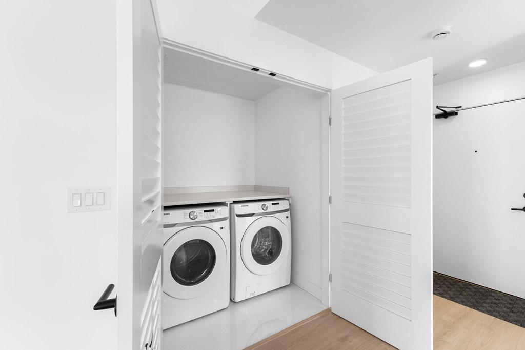 A laundry room with two washing machines and a door open.