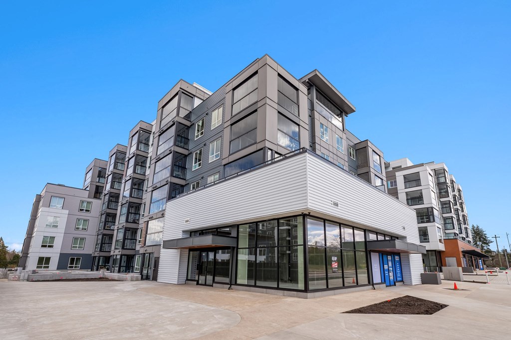 A modern multi-story building with a flat roof and large glass windows.