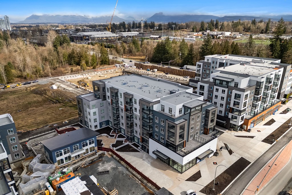 A construction site with a large building under construction in the foreground and other buildings in the background.