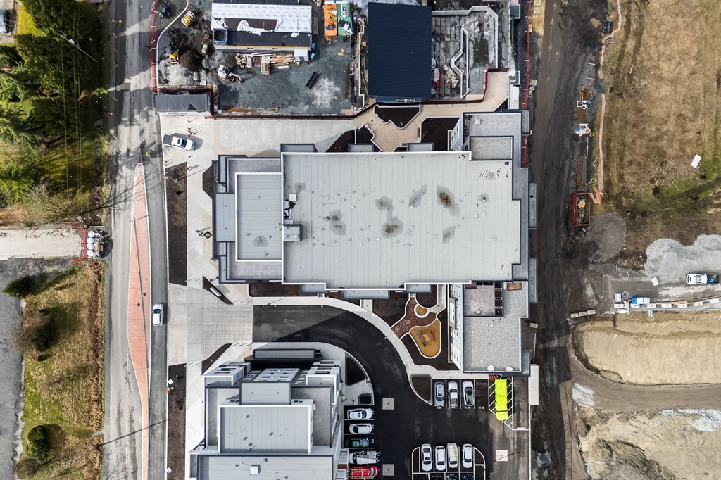An aerial view of a large industrial building with a parking lot in front.