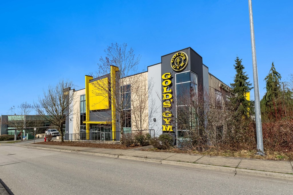 A building with a yellow and black sign that says Gold's Gym.