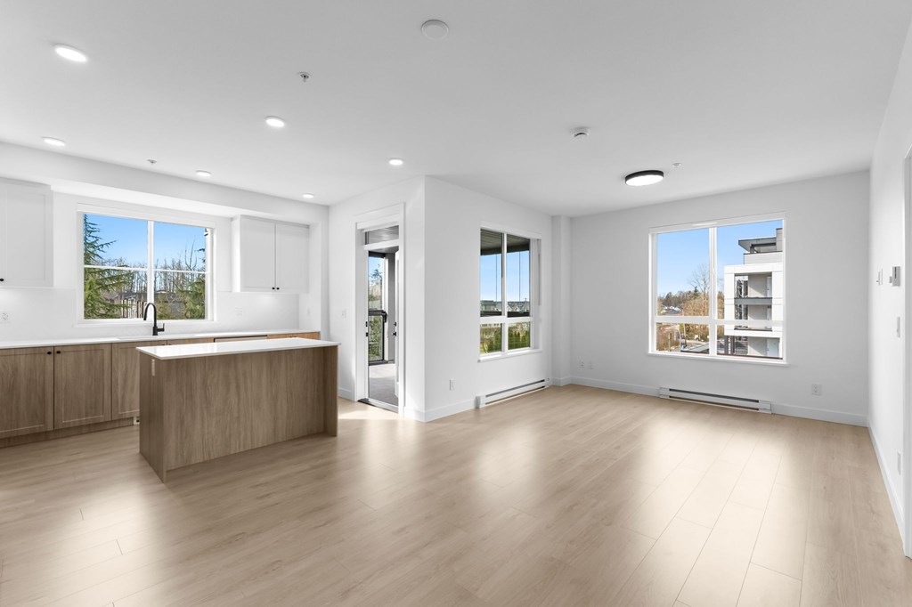 A spacious, empty room with wooden floors and white walls.