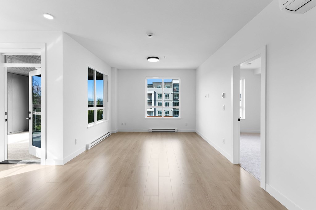 A spacious room with wooden floors and white walls.