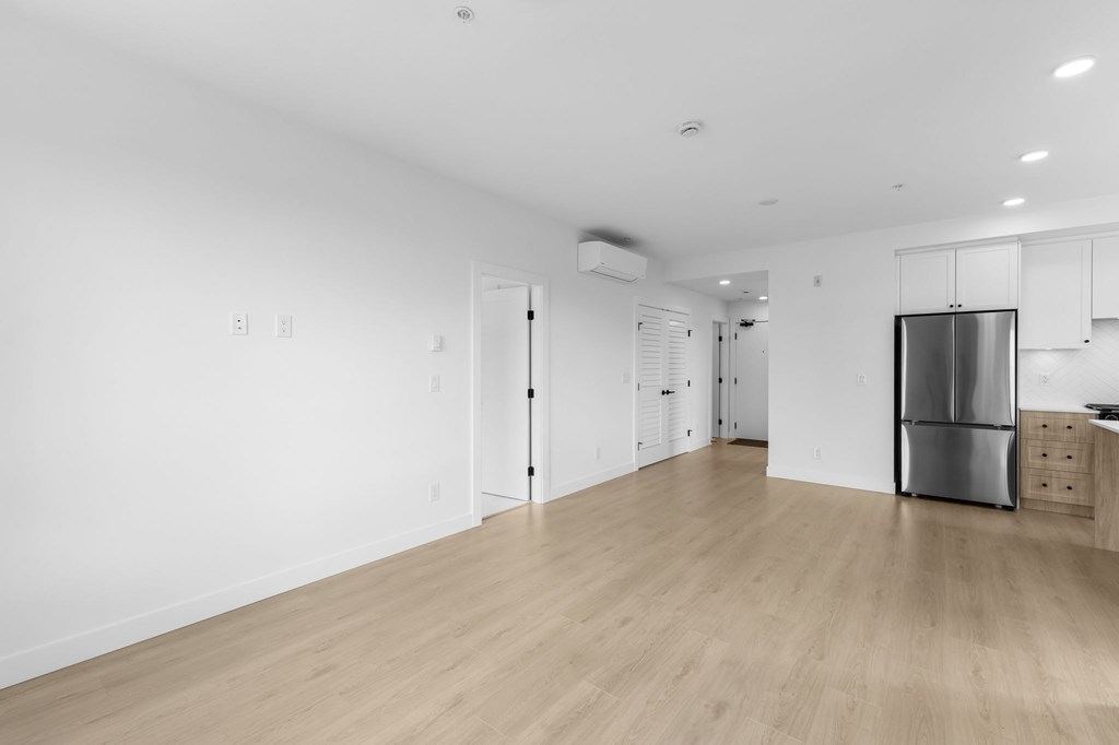 A kitchen with a refrigerator, cabinets, and a counter.