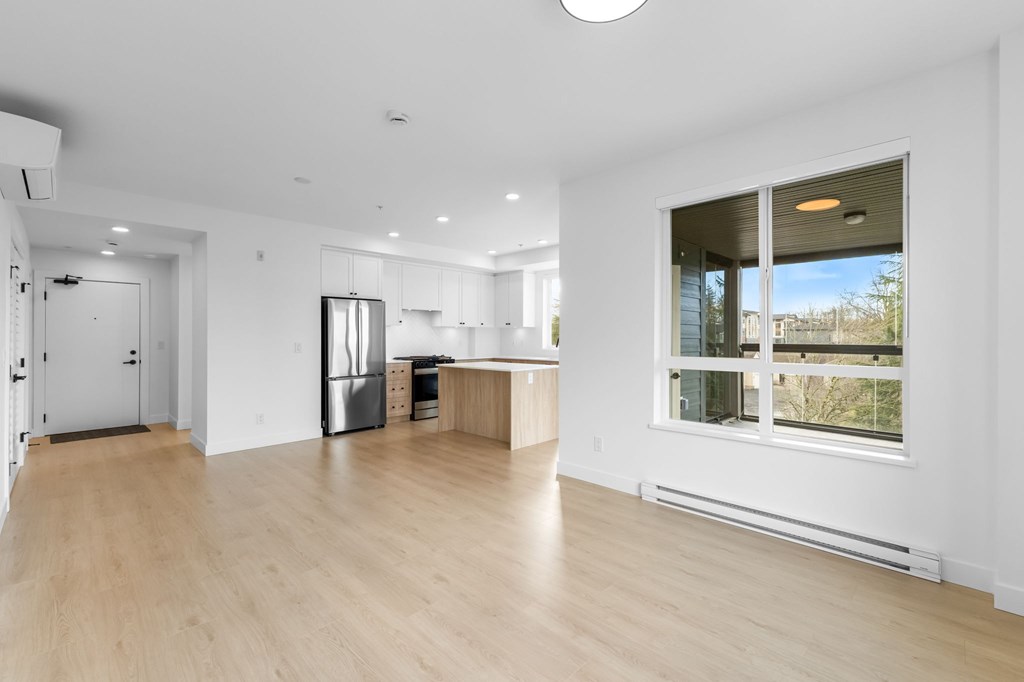 A spacious kitchen with a refrigerator, sink, and a window overlooking a balcony.