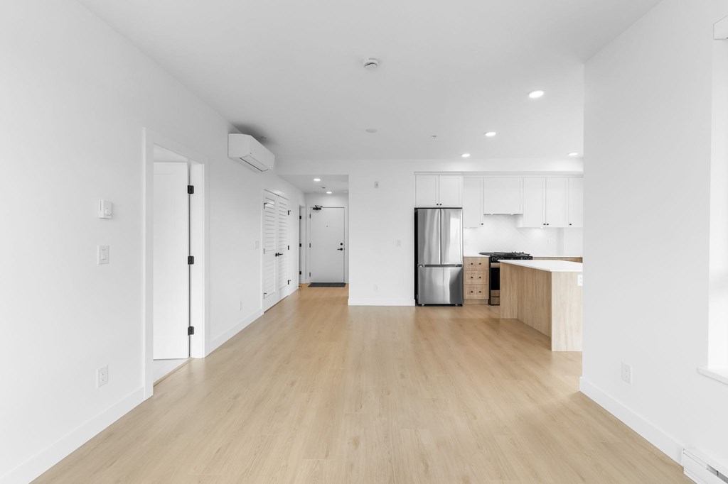 A long, empty room with wooden floors and white walls.