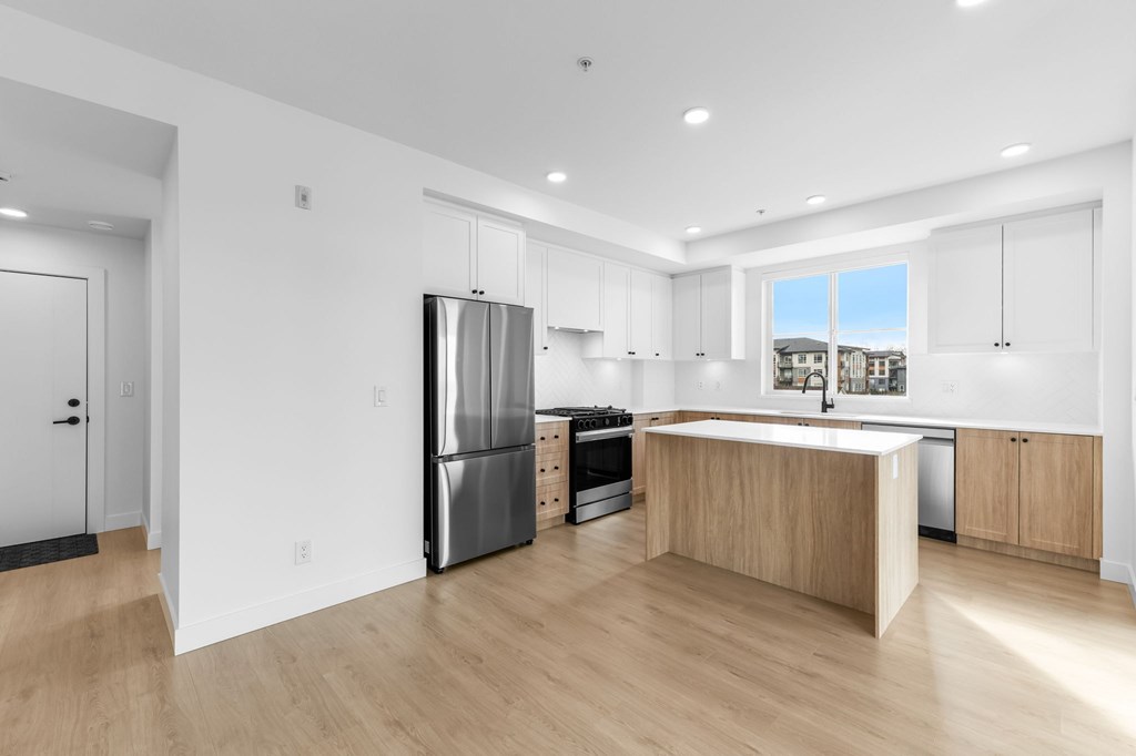A kitchen with a refrigerator, stove, and sink.