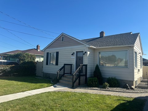 A house with a grey roof and a white wall with a black railing.