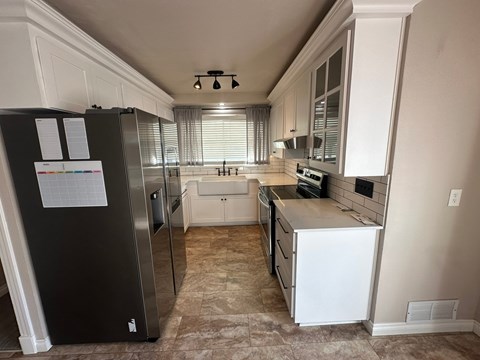 A kitchen with a black fridge and white cabinets.