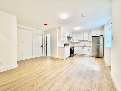 A kitchen with white cabinets and a wooden floor.