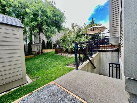 A backyard with a concrete patio and a black metal railing.