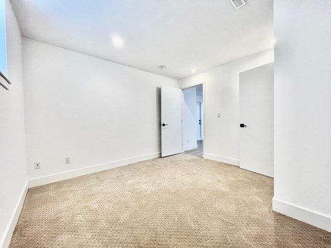 A room with a carpeted floor and two doors.