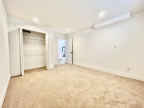 A spacious room with a carpeted floor and a doorway leading to another room.