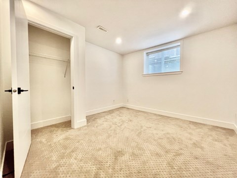 A room with a carpeted floor and a window with blinds.