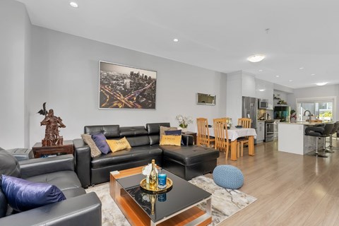 A modern living room with a black leather couch and a wooden coffee table.