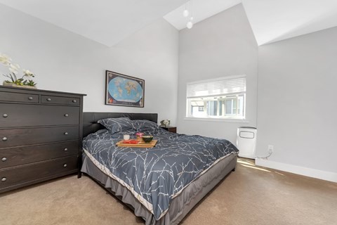 A bedroom with a bed, dresser, and window.