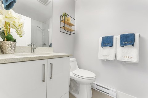 A white toilet in a bathroom with a white cabinet and a white sink.