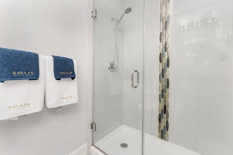 A white bathroom with a glass shower door and a shower head.