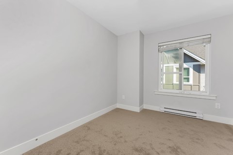 A room with a window and a carpeted floor.